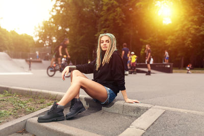 Portrait of young woman sitting on footpath