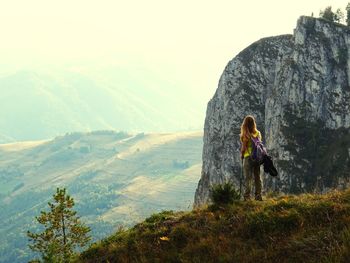 Woman sitting on mountain against sky