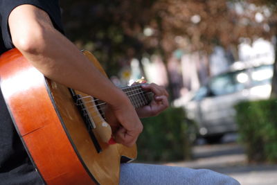 Midsection of man playing guitar