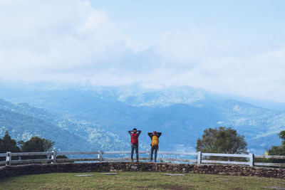 Rear view of man standing on mountain against sky