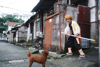 Woman with dog standing by umbrella on street