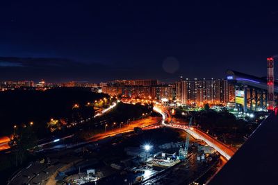 High angle view of illuminated street amidst buildings at night