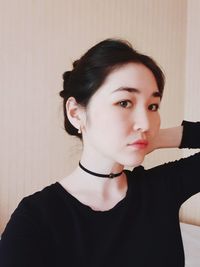 Portrait of a beautiful young woman against wall at home