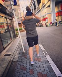 Rear view of woman standing on road in city