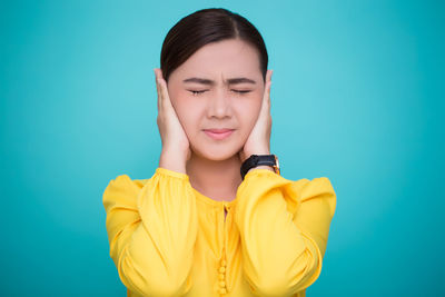 Portrait of young woman against blue background