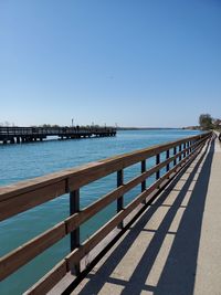 Pier over sea against clear blue sky