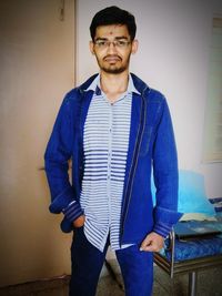 Portrait of young man standing against wall