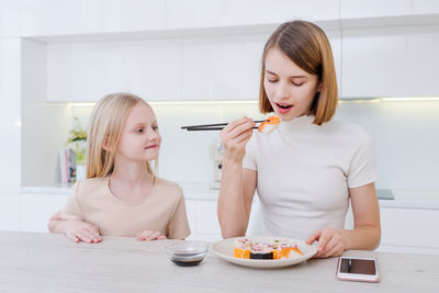 Portrait of smiling young woman eating food at home