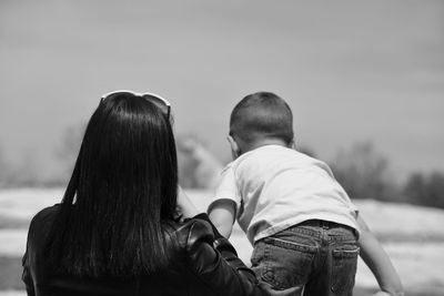 Rear view of mother and son against sky