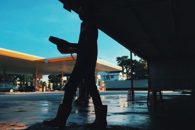 Silhouette man standing on street against sky in city