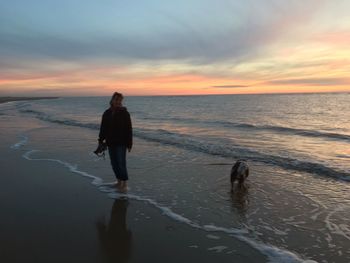 Full length of man standing on beach against sky during sunset