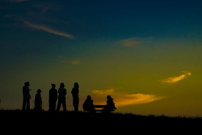 Silhouette people at beach against sky during sunset