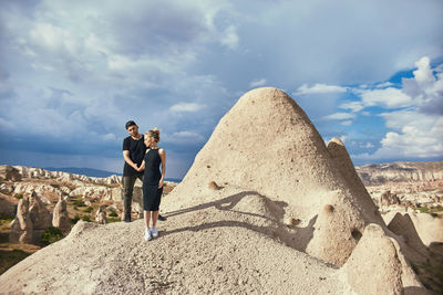 Friends standing on rock against sky