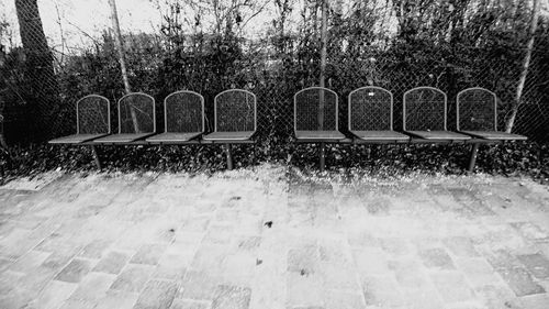 Empty chairs by swimming pool in park during winter