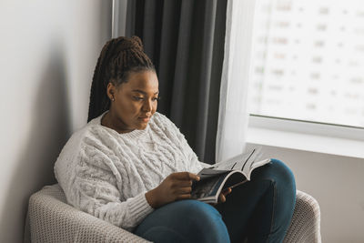 Side view of young man sitting on sofa at home