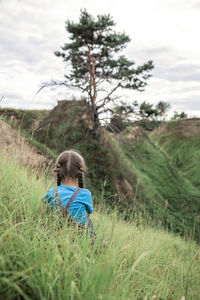 Rear view of girl sitting on field