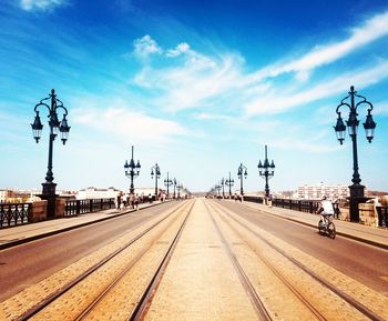 Diminishing perspective of city street against sky during sunny day