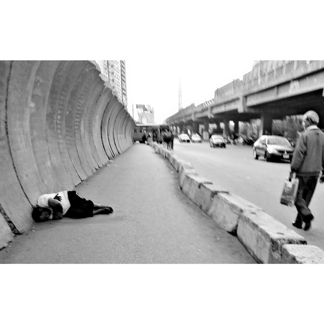 LOW SECTION OF MAN WALKING ON ROAD IN CITY AGAINST CLEAR SKY