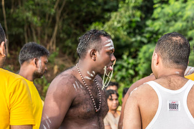 Portrait of young men standing against people in water