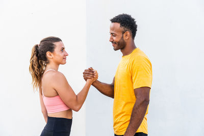 Side view of young woman exercising against white background