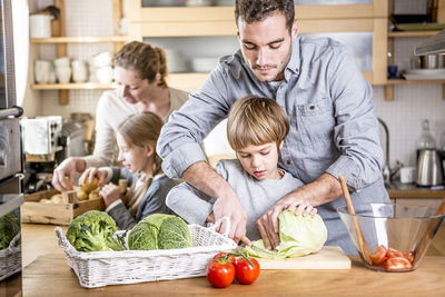Family preparing salad in kitchen