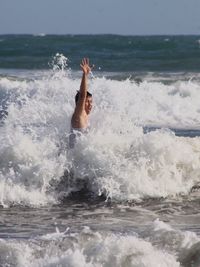 Young man enjoying in sea wave on sunny day