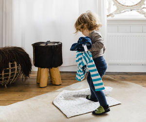 Full length of baby girl holding clothes while standing at home