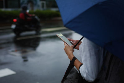 Midsection of woman using mobile phone on city street