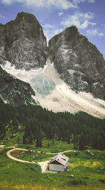 Rocky mountain with trees on grass and house