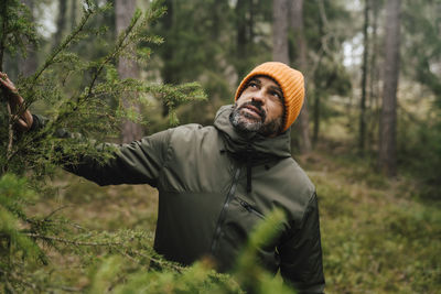 Mature male explorer looking up while hiking in forest