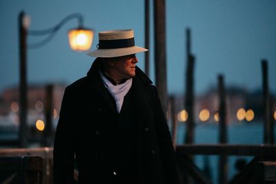 Man wearing hat standing in city at night