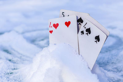 Playing cards stuck in a pile of snow outdoors