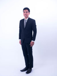 Portrait of young man standing against white background