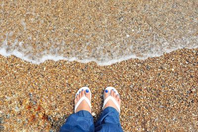 Low section of woman standing at sandy beach