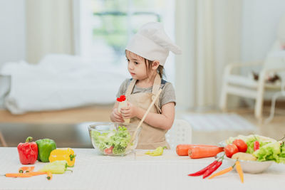 Girl holding ice cream on table at home