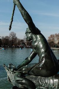 Close-up of statue by river against sky