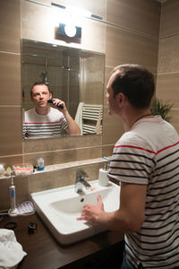 Reflection of man shaving in mirror at home