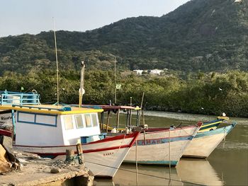 Boats moored on shore against mountains