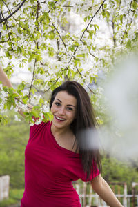 Portrait of beautiful smiling young woman below tree branches