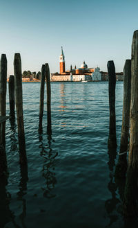 Wooden posts in sea against clear sky