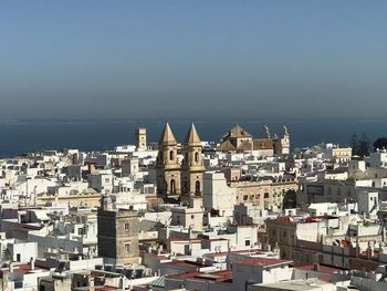 Buildings by sea against clear sky