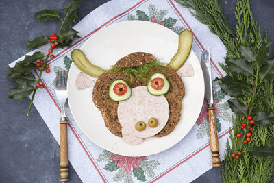 Sandwich in the form of a cheerful bull made of bread,s ausages and vegetables