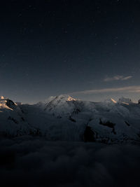 Scenic view of snowy covered mountains against sky at night