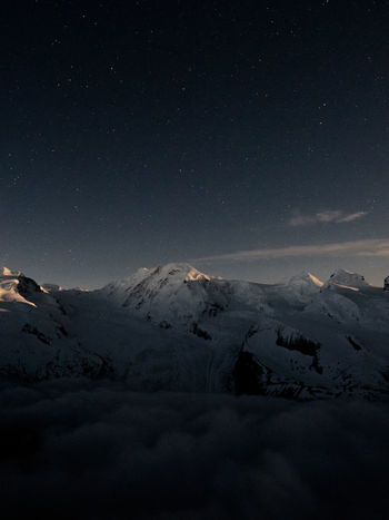 Scenic view of snowy covered mountains against sky at night