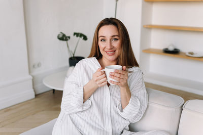 Young woman using mobile phone while sitting in bathroom