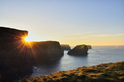 Scenic view of rocks in sea against sky during sunset