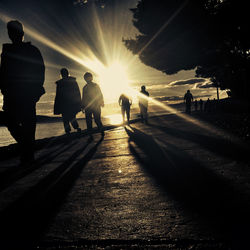 Silhouette people walking on street at sunset