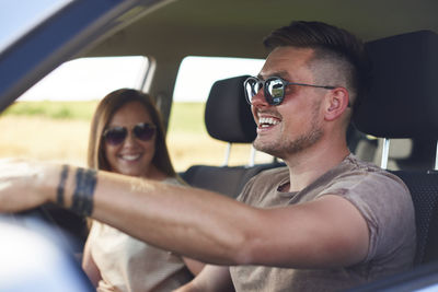 Smiling couple wearing sunglasses in car