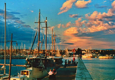 Boats moored in harbor at sunset