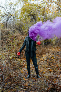 Woman with purple distress flare standing on field